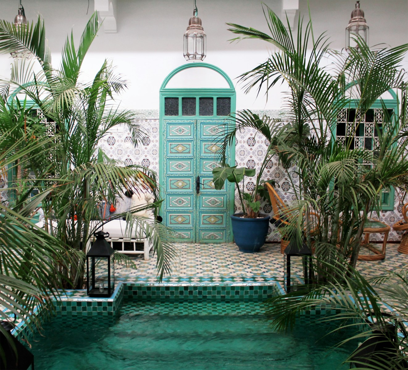 une piscine avec une porte verte, entourée de palmiers Louer en longue durée ou en courte durée au Maroc